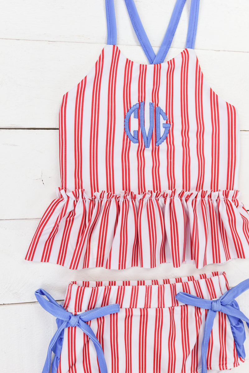 a little girl's red and white striped swimsuit with a monogrammed