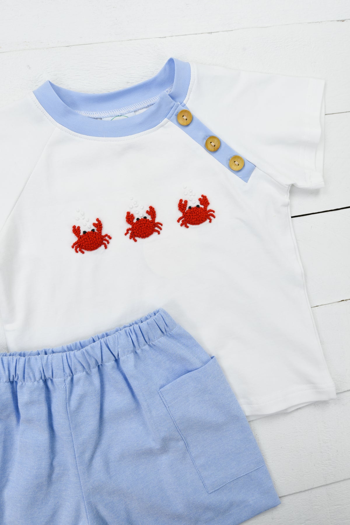 a white shirt and blue shorts with crab appliques