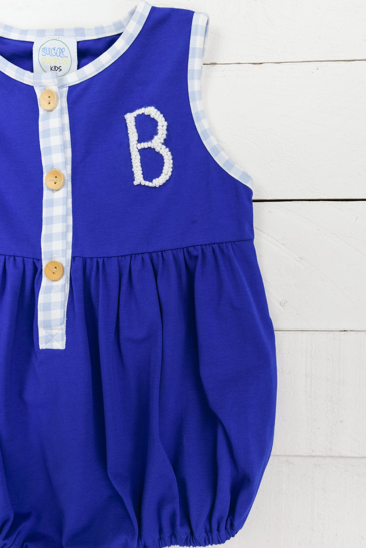 a blue romper with a letter b on it