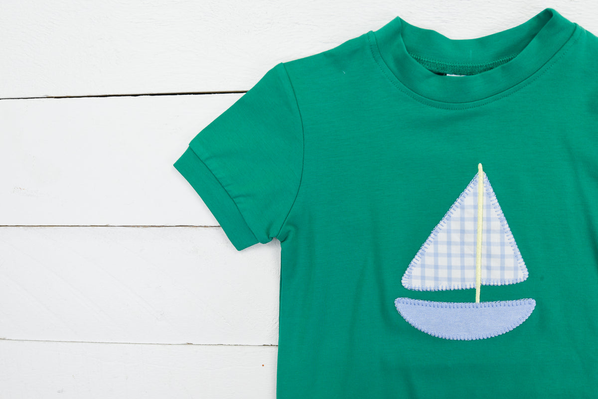 a green shirt with a sailboat applique on it