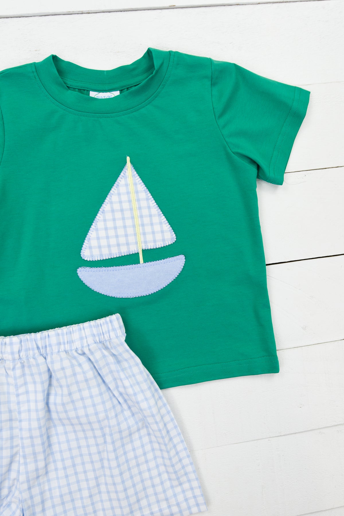 a green shirt and shorts with a sailboat on it