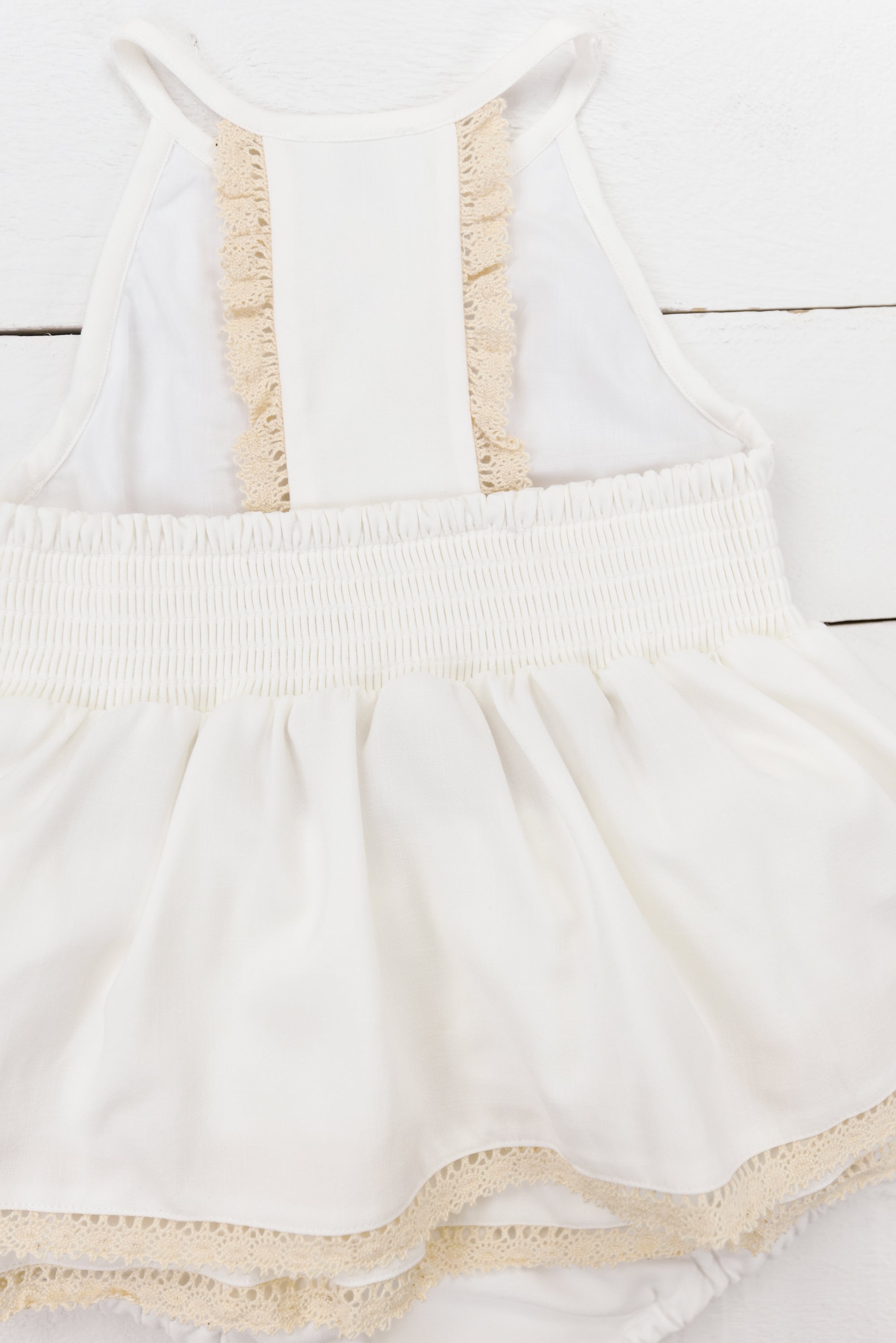 a baby girl's white dress on a wooden floor