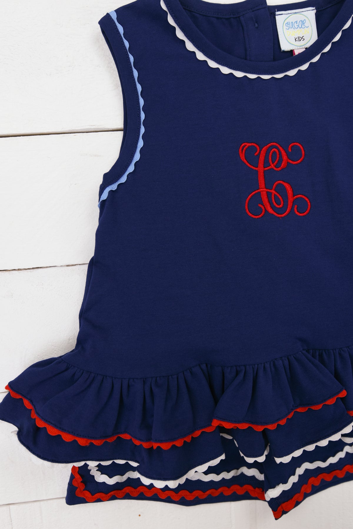 a little girl's blue dress with red and white ruffles