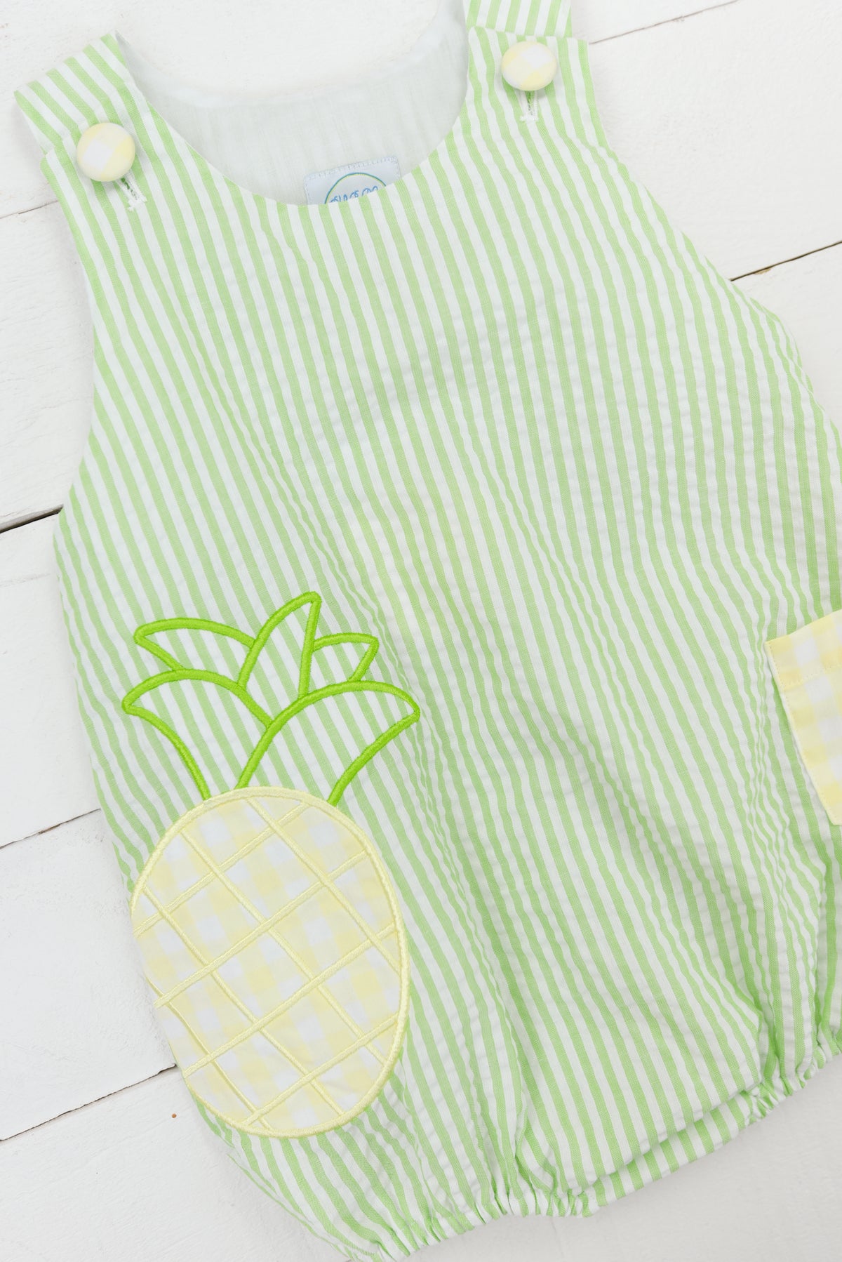 a green and white striped romper with a pineapple applique